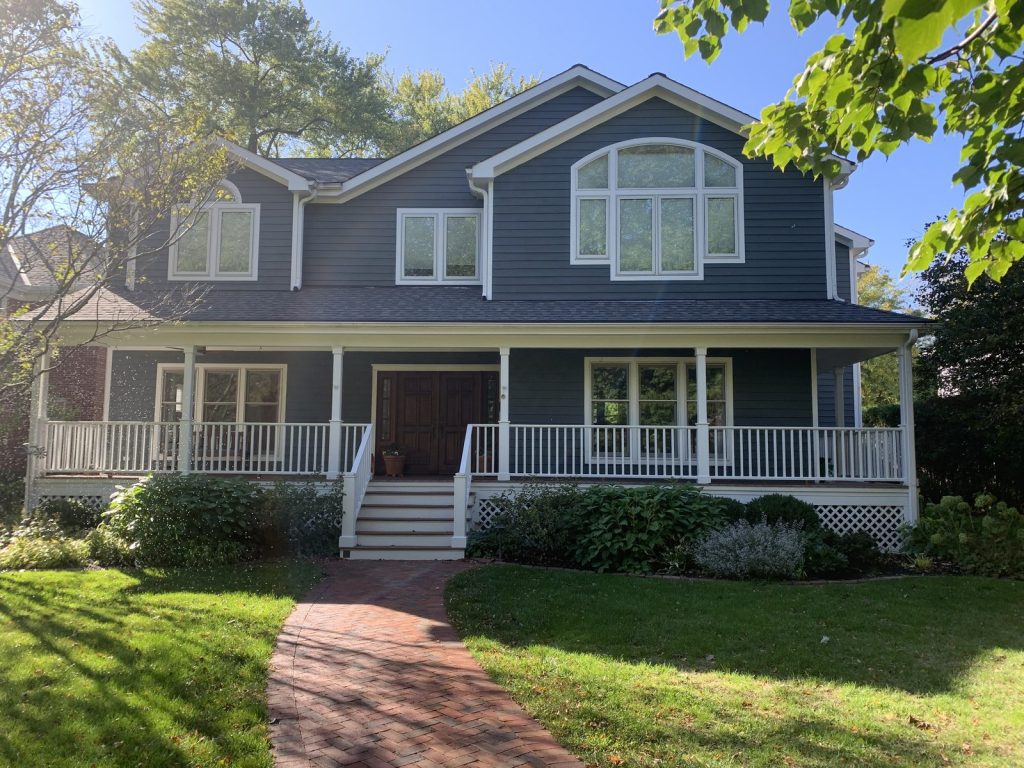 Freshly painted blue two-story home with white trim and wraparound porch, North Shore