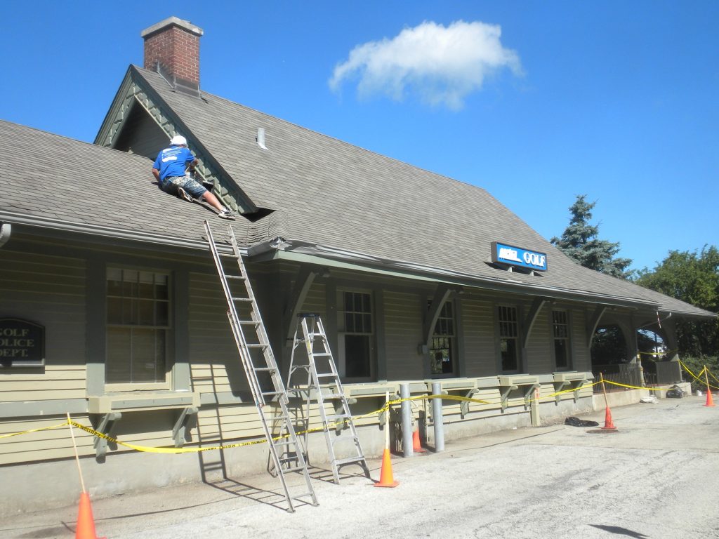 Pete the Painter crew on ladders painting the Golf Metra station roofline