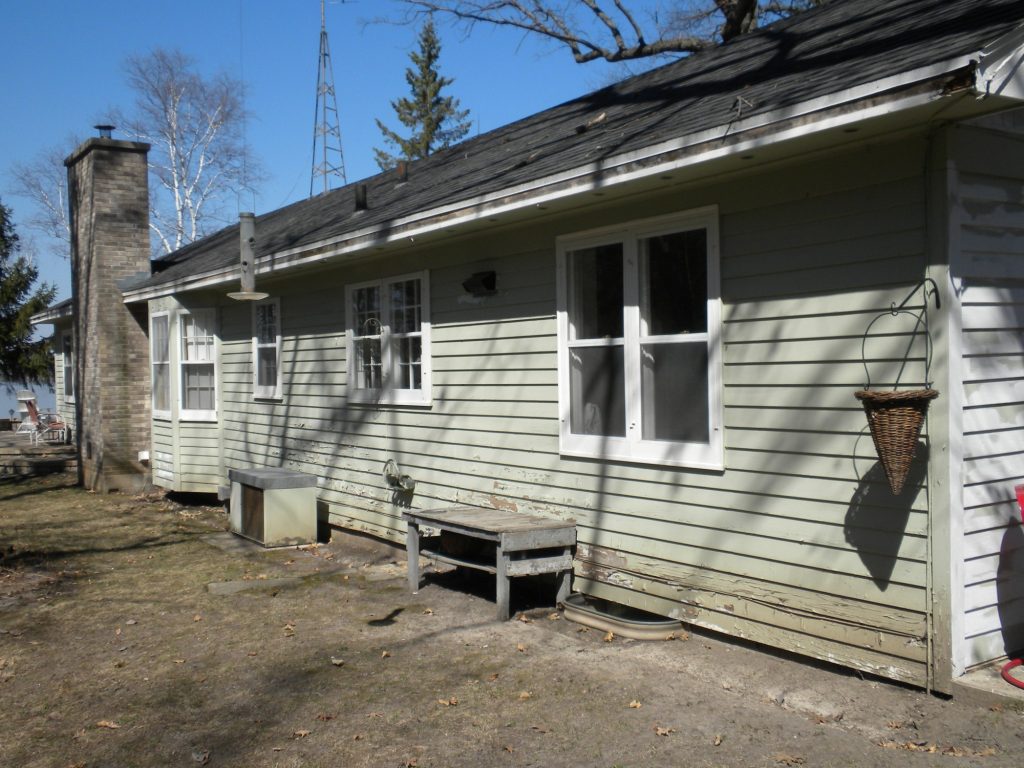 Lake house in Green Lake, Wisconsin before painting: faded siding, back wall