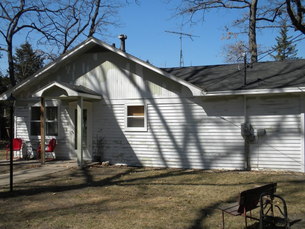 Lake house in Green Lake, Wisconsin before painting: faded siding, faded siding