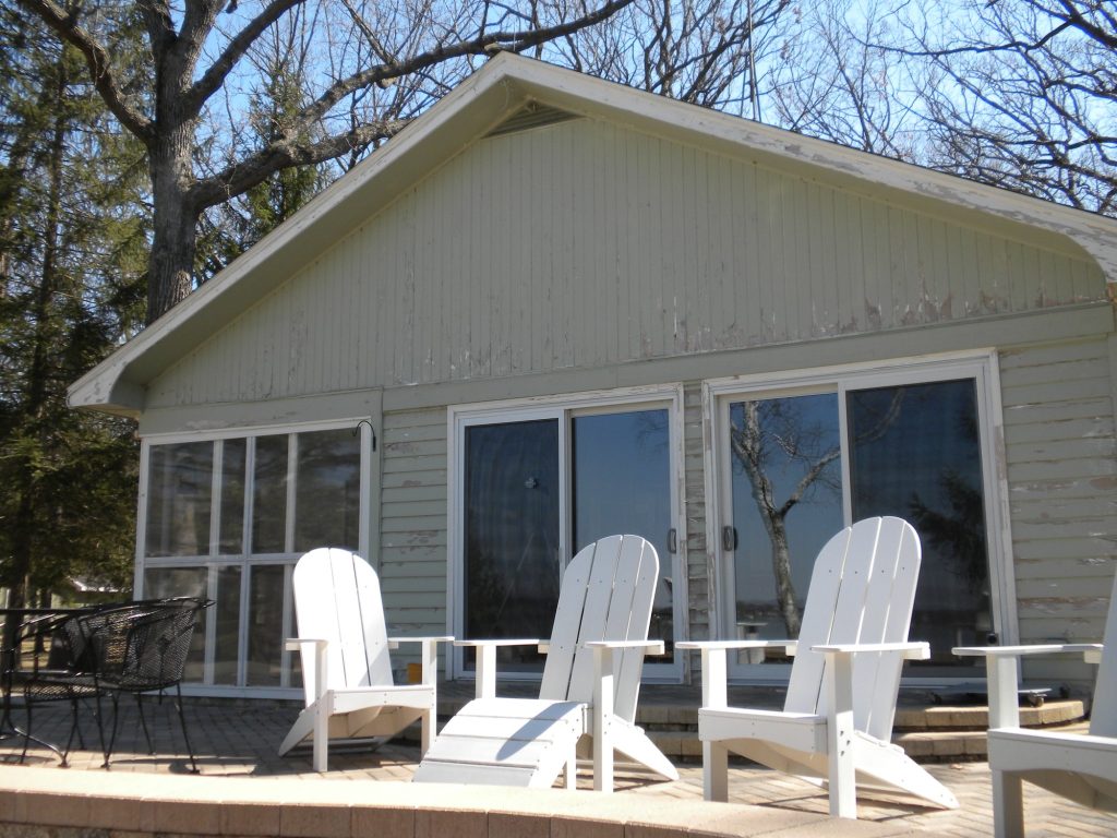 Lake house in Green Lake, Wisconsin before painting: faded siding, porch