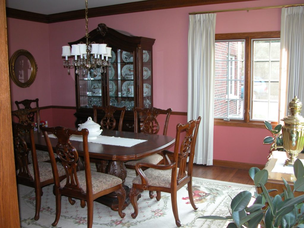 Formal dining room with rose-colored walls, dark wood furniture, and a crystal chandelier painted by Pete the Painter