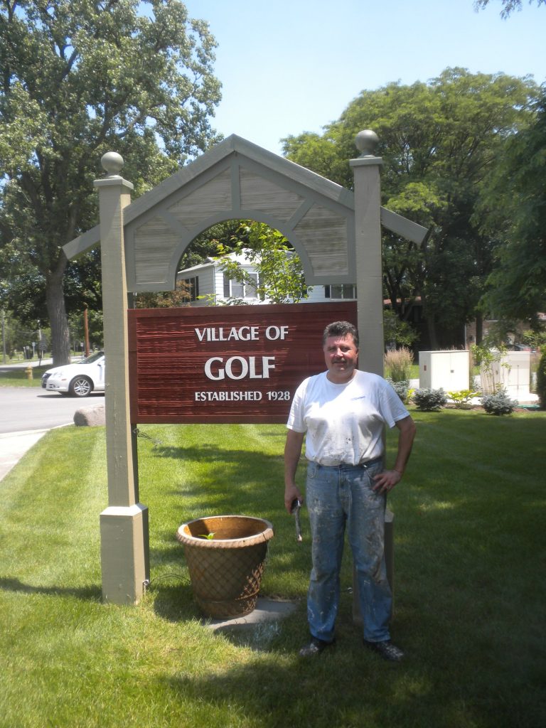 Village of Golf sign with Pete Wirtz after repainting the station