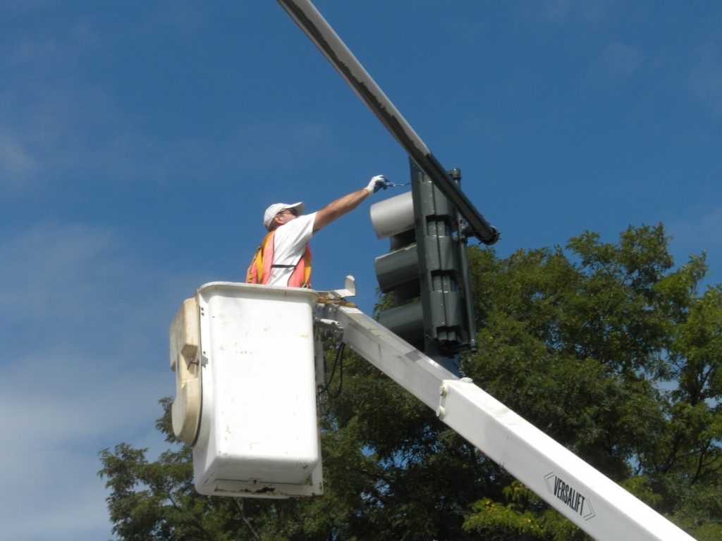 Painter aloft finishing a traffic signal head in Winnetka