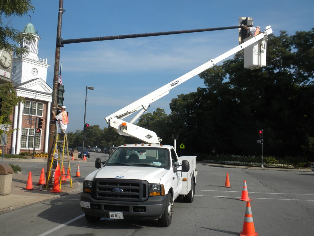 Traffic cones and bucket truck while painting signal poles in downtown Winnetka
